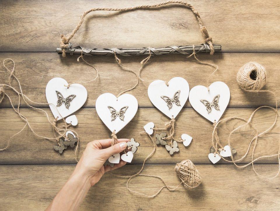 person holding heart windchimes wooden plank with spool